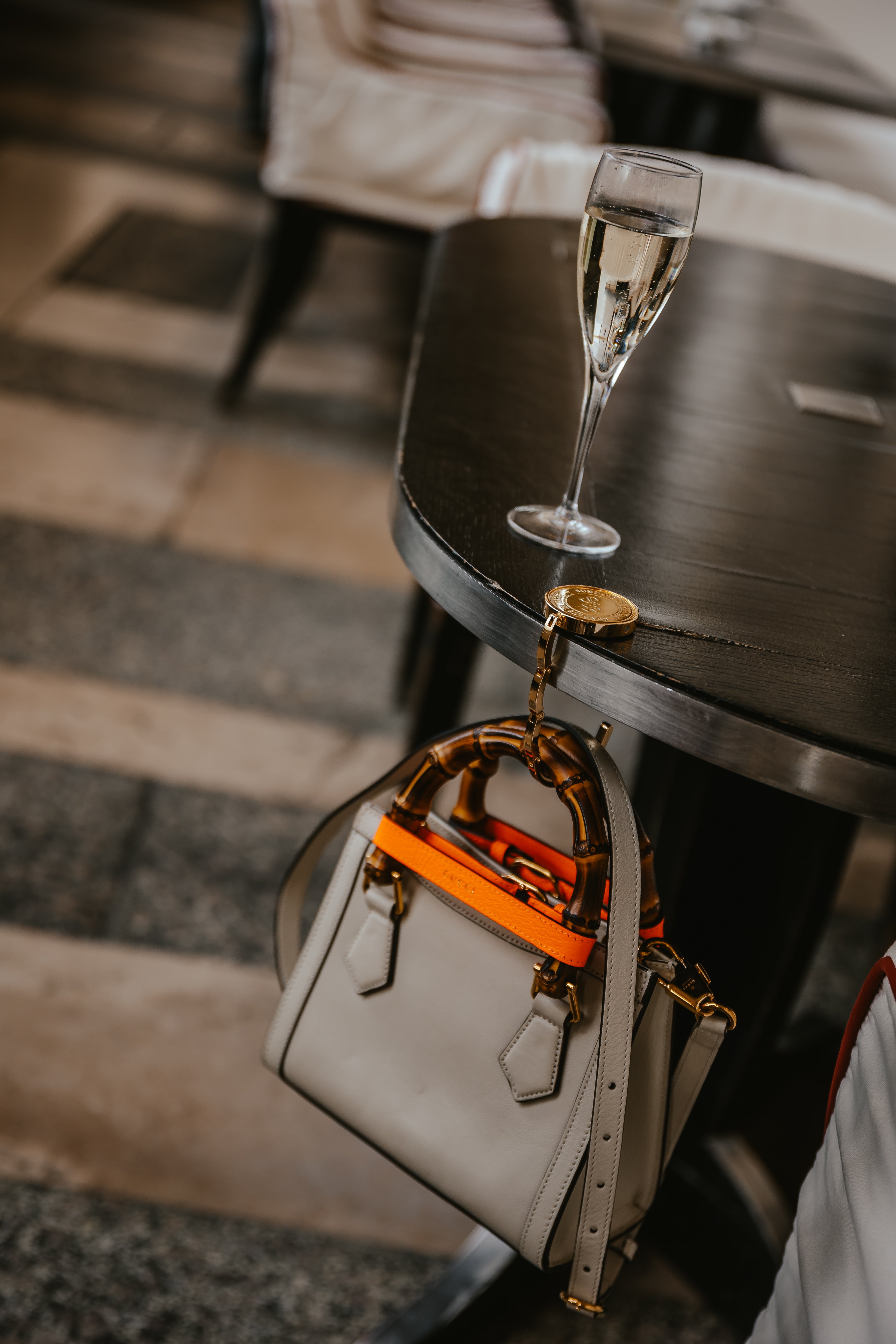 Sundays in Paris Le Petite gold purse hook holding a handbag on a restaurant table